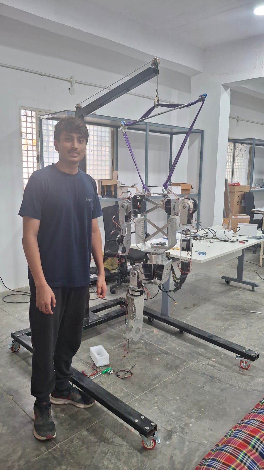 Aryaman next to the 52-DOF humanoid on its test gantry